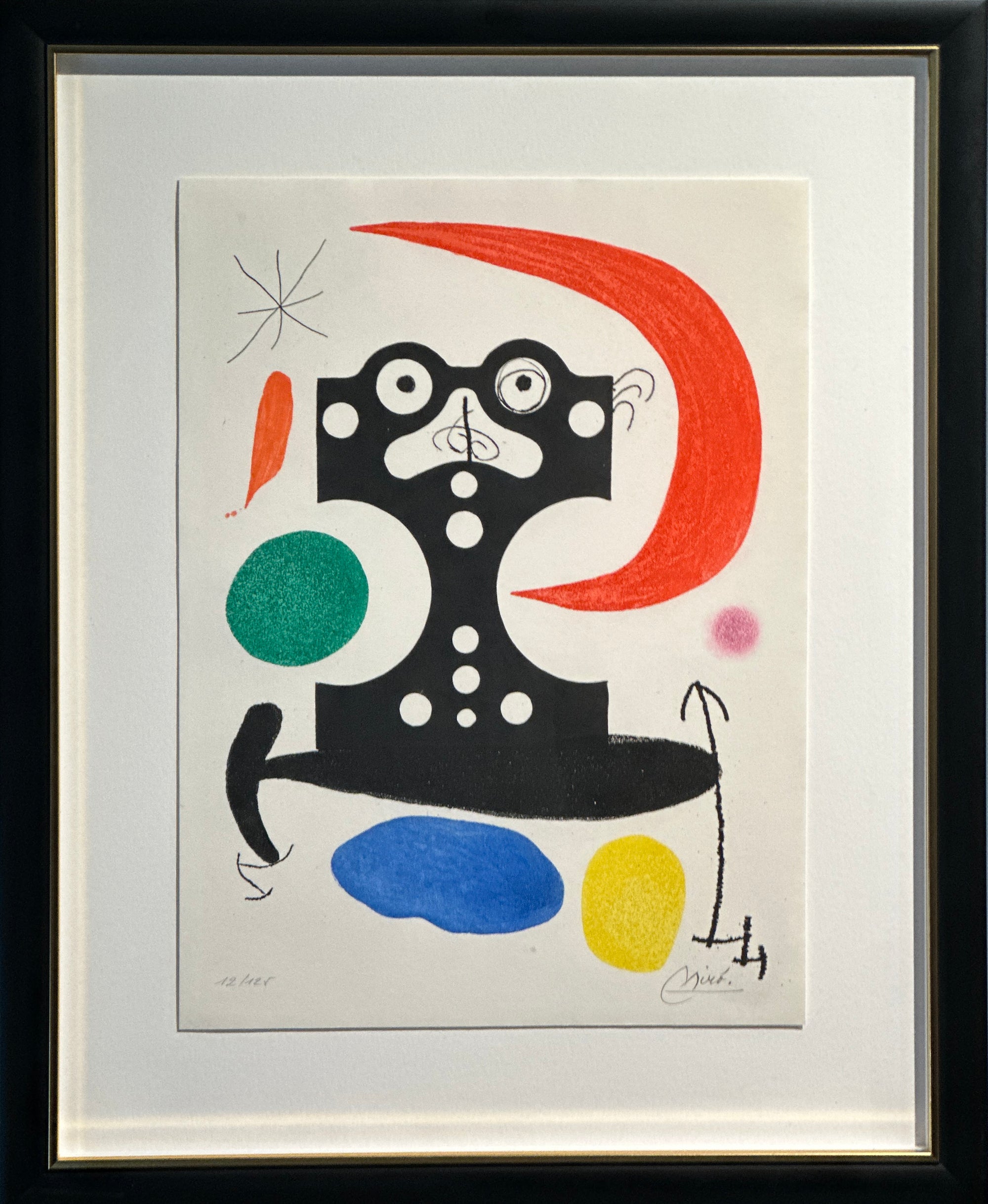 A framed abstract art print featuring a bold black figure with white circular details, a large red crescent shape, and several colored shapes in green, blue, yellow, and pink on a white background, enclosed in a black frame with a white mat.